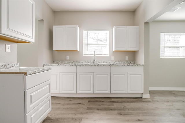 kitchen featuring white cabinetry, sink, and light hardwood / wood-style flooring