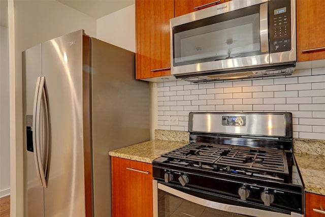 kitchen with stainless steel appliances, tasteful backsplash, and light stone counters