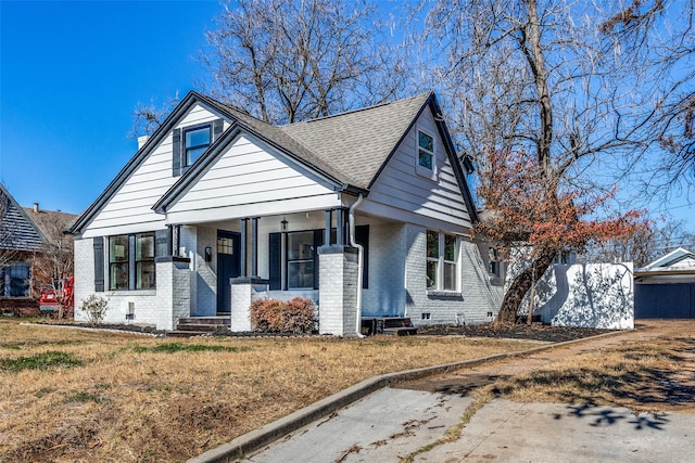 bungalow-style home featuring covered porch and a front lawn