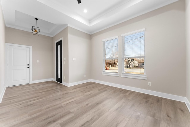 entrance foyer featuring ornamental molding, light wood-type flooring, and a tray ceiling