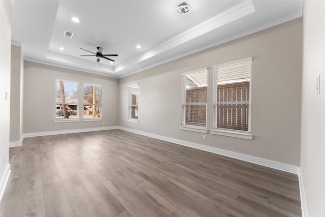 unfurnished room with a raised ceiling, crown molding, hardwood / wood-style flooring, and ceiling fan