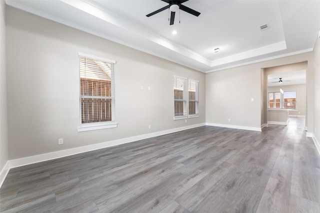 spare room with hardwood / wood-style floors, a tray ceiling, ornamental molding, and ceiling fan