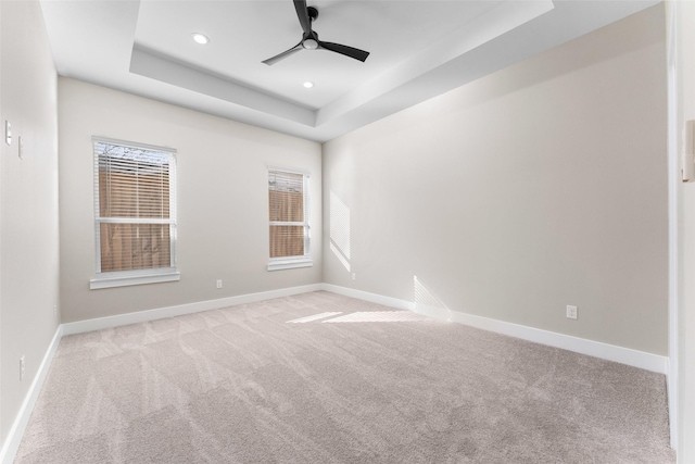 carpeted empty room featuring a tray ceiling and ceiling fan