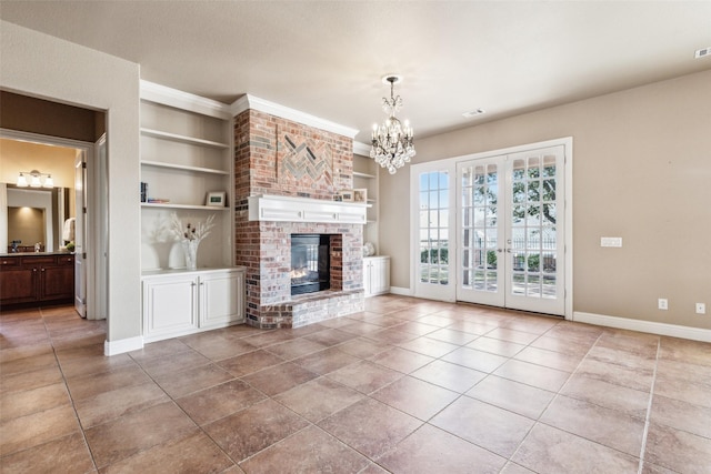 unfurnished living room with built in shelves, an inviting chandelier, a fireplace, and tile patterned flooring