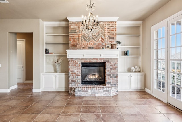 unfurnished living room with a notable chandelier, a brick fireplace, light tile patterned floors, and built in features