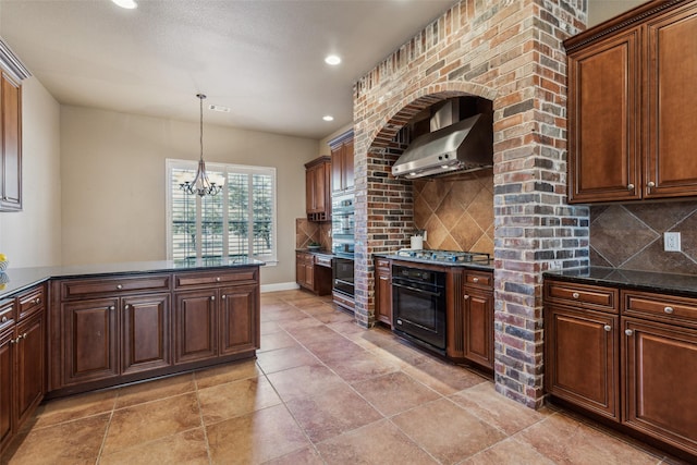 kitchen featuring wall chimney range hood, black oven, backsplash, hanging light fixtures, and stainless steel gas cooktop