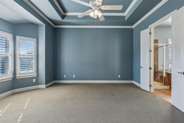 empty room with a raised ceiling, crown molding, carpet floors, and ceiling fan