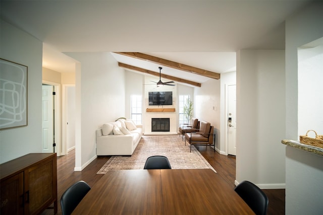 living room featuring dark hardwood / wood-style flooring, vaulted ceiling with beams, ceiling fan, and a fireplace