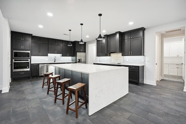 kitchen featuring stainless steel appliances, a spacious island, light countertops, visible vents, and custom range hood