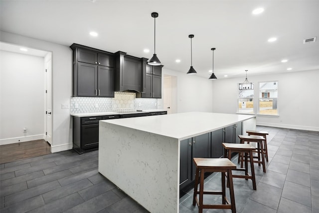 kitchen featuring visible vents, decorative backsplash, a spacious island, custom exhaust hood, and light countertops