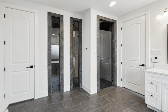 bathroom with baseboards, a shower stall, vanity, and tile patterned floors