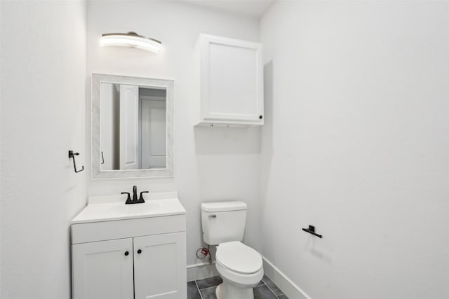 bathroom featuring toilet, vanity, and baseboards