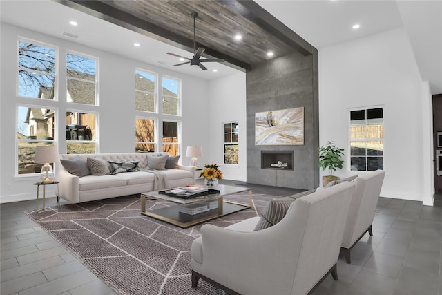 living area with recessed lighting, visible vents, a fireplace, and a high ceiling