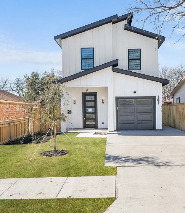 modern farmhouse featuring a garage, concrete driveway, fence, a front lawn, and board and batten siding