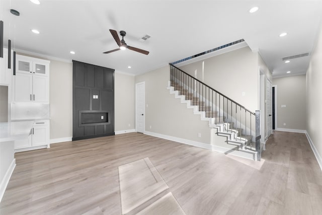 unfurnished living room with visible vents, baseboards, ornamental molding, stairway, and light wood-type flooring