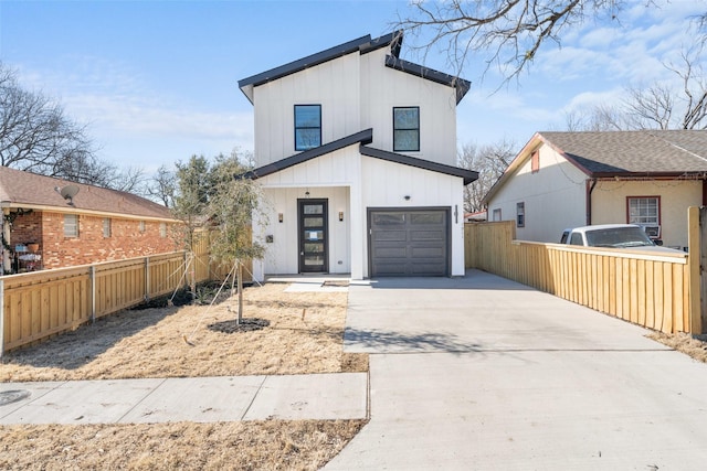 contemporary home with board and batten siding, a garage, fence, and concrete driveway