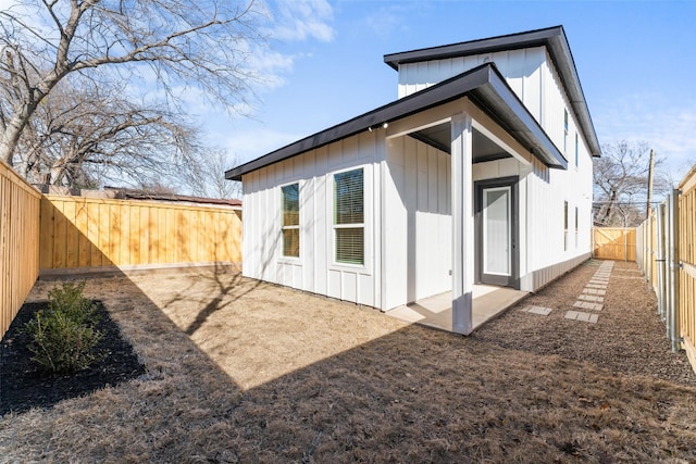 rear view of property with a fenced backyard and board and batten siding