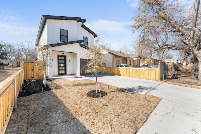 view of front of home with a fenced front yard, concrete driveway, and a garage