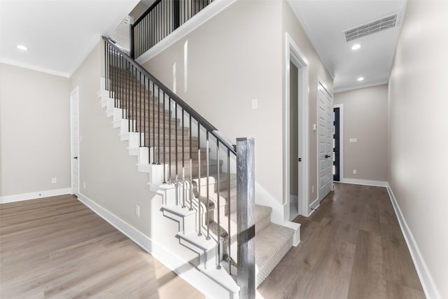 stairway with recessed lighting, visible vents, baseboards, and wood finished floors