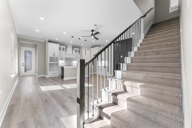 stairs featuring ceiling fan, recessed lighting, wood finished floors, baseboards, and ornamental molding