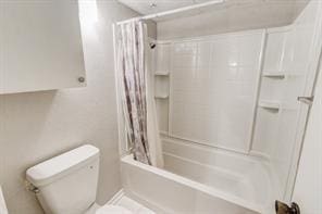 bathroom with toilet and shower / bath combo with shower curtain