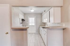 kitchen featuring sink, exhaust hood, and white cabinets