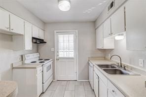 kitchen with white cabinetry, sink, light tile patterned floors, and white appliances