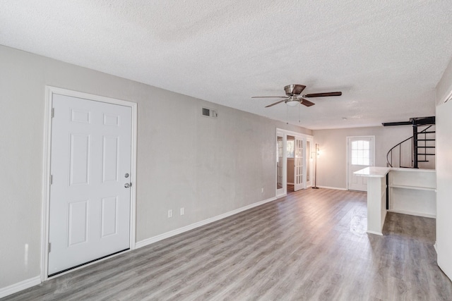 unfurnished living room featuring light wood-type flooring, a textured ceiling, and ceiling fan