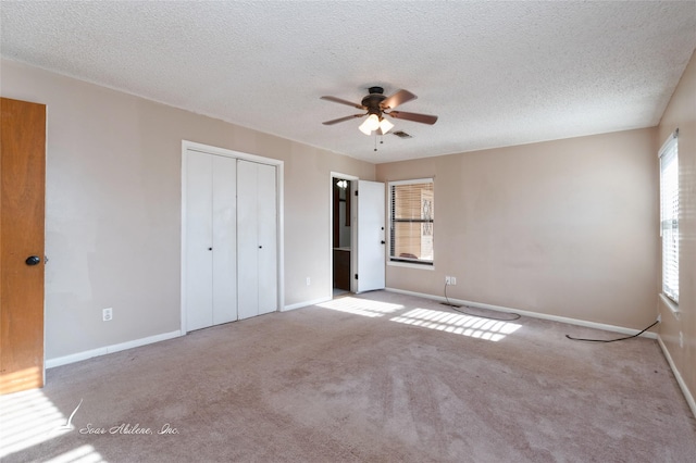 unfurnished bedroom with light carpet, a textured ceiling, a closet, and ceiling fan