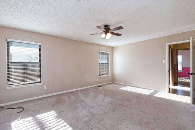 unfurnished room featuring ceiling fan, light carpet, and a textured ceiling