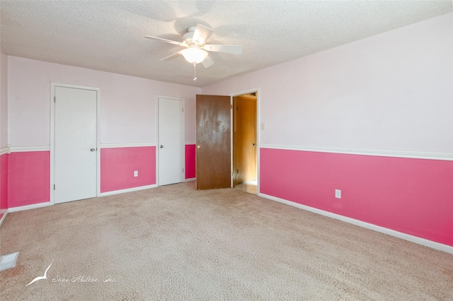 unfurnished bedroom with light carpet, a textured ceiling, and ceiling fan