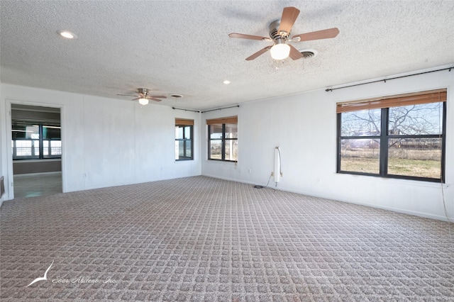 spare room featuring ceiling fan, a healthy amount of sunlight, carpet, and a textured ceiling