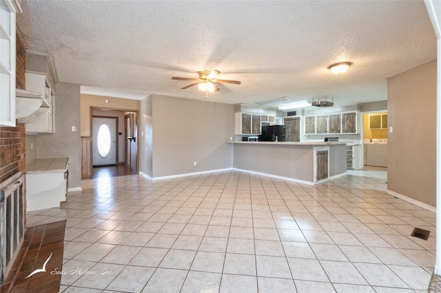 kitchen with a textured ceiling, light tile patterned floors, fridge, kitchen peninsula, and white cabinets