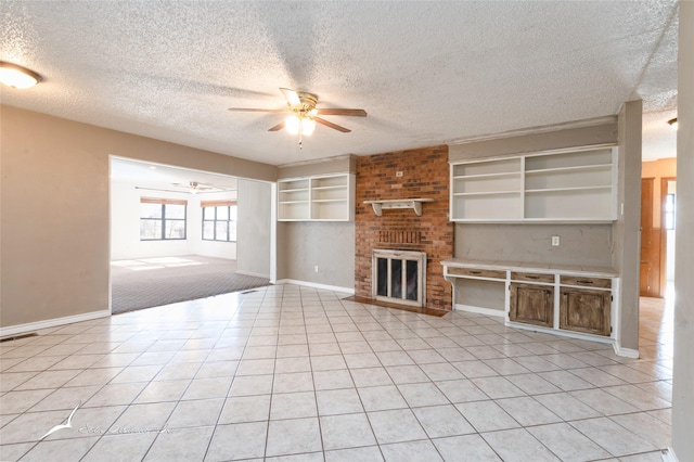 unfurnished living room featuring light tile patterned flooring, ceiling fan, a fireplace, and a textured ceiling