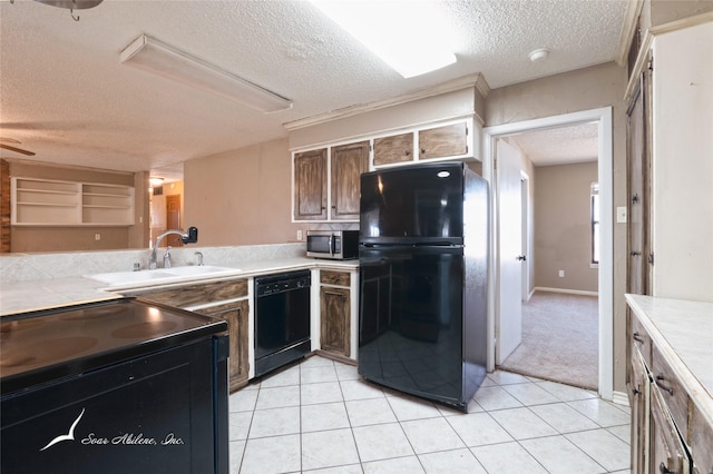 kitchen with sink, light tile patterned floors, black appliances, and a textured ceiling