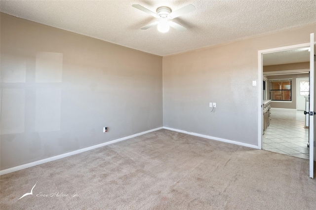 empty room featuring ceiling fan, light colored carpet, and a textured ceiling