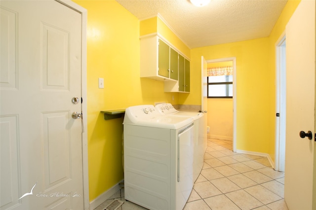 laundry room with cabinets, washing machine and clothes dryer, light tile patterned flooring, and a textured ceiling