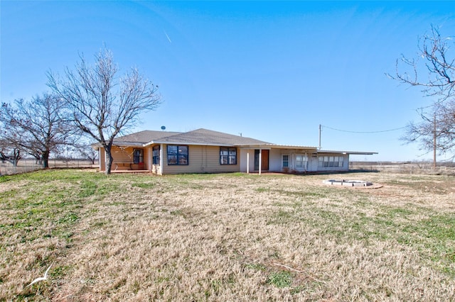 rear view of property with a fire pit and a yard