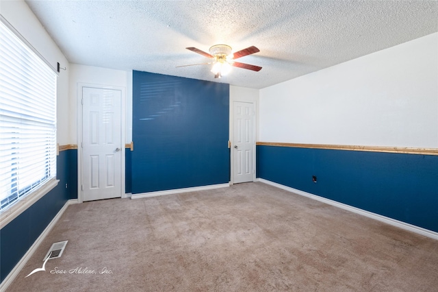 carpeted spare room with ceiling fan and a textured ceiling