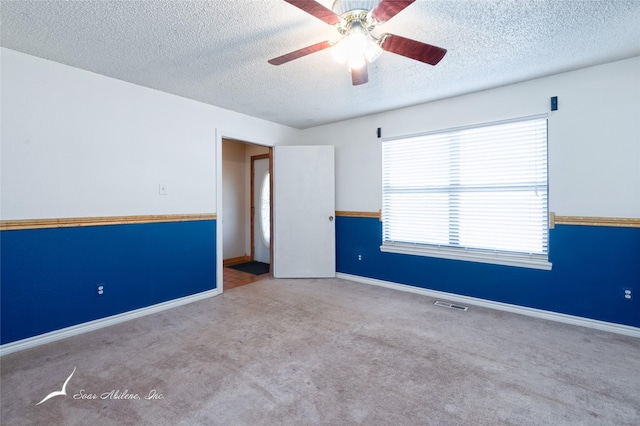 spare room featuring ceiling fan, light colored carpet, and a textured ceiling