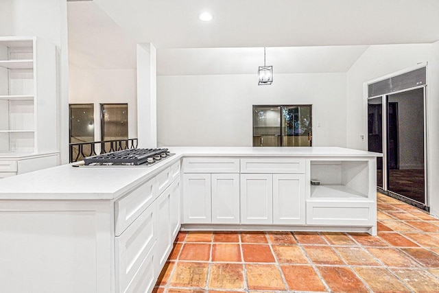 kitchen with black built in refrigerator, decorative light fixtures, vaulted ceiling, stainless steel gas stovetop, and white cabinets