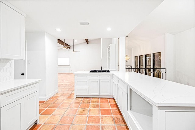 kitchen with stainless steel gas stovetop, lofted ceiling with beams, and white cabinets