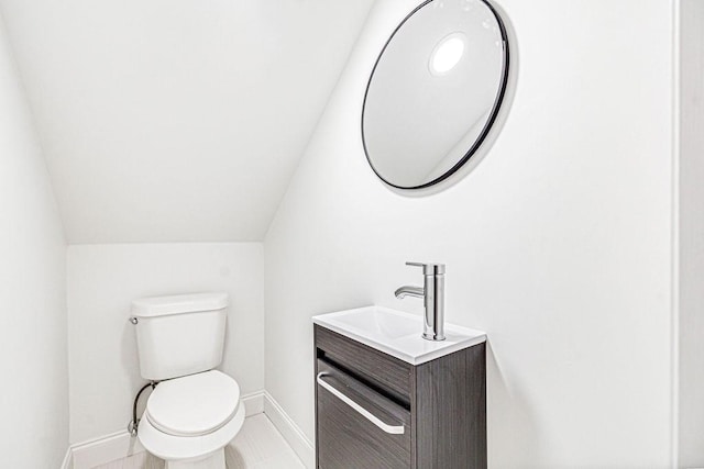 bathroom featuring vanity, vaulted ceiling, and toilet