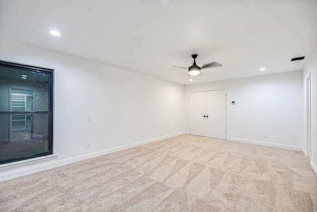 spare room featuring ceiling fan and light carpet