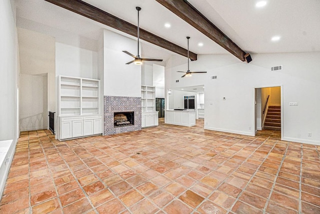 unfurnished living room with beamed ceiling, ceiling fan, high vaulted ceiling, and a fireplace