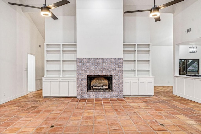 unfurnished living room featuring high vaulted ceiling, a fireplace, built in features, and ceiling fan