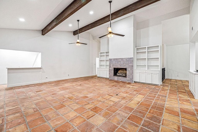 unfurnished living room featuring a tiled fireplace, vaulted ceiling with beams, and ceiling fan