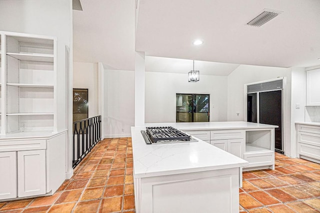 kitchen featuring pendant lighting, white cabinetry, a center island, vaulted ceiling, and stainless steel gas stovetop