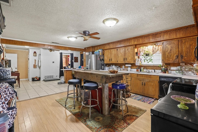 kitchen with dishwashing machine, sink, stainless steel fridge, ceiling fan, and light hardwood / wood-style floors