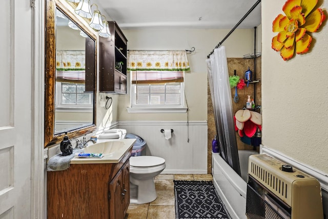 full bathroom featuring heating unit, shower / bath combination with curtain, tile patterned flooring, vanity, and toilet